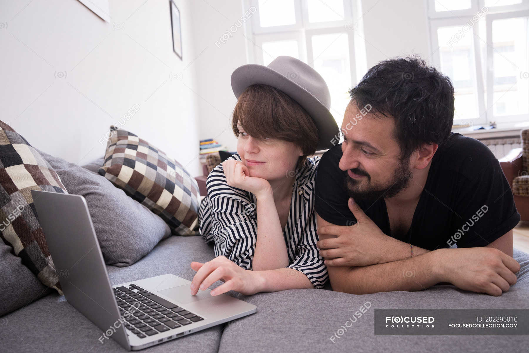 A Young Couple Is Streaming Tv Series On The Computer While