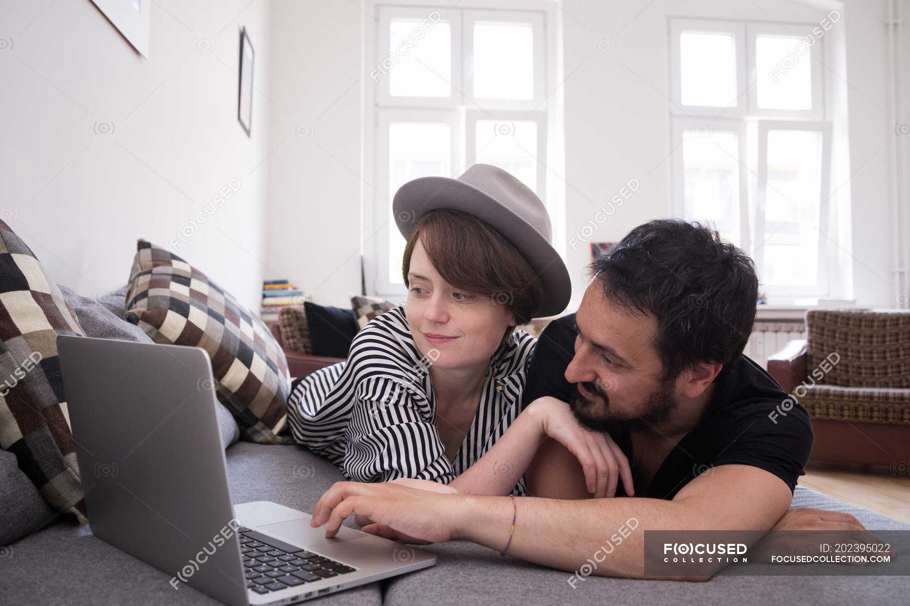 A Young Couple Is Streaming Tv Series On The Computer While