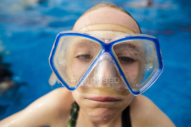 A girl in swimming pool wearing goggles and making a funny face. — Stock Photo
