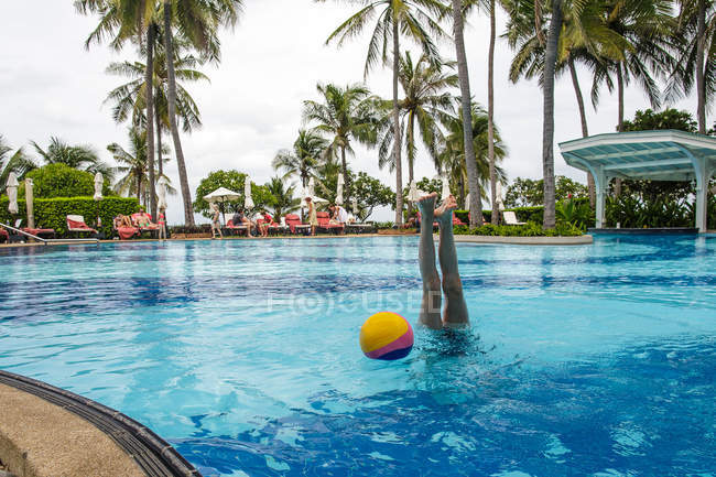 Una chica se está divirtiendo y hace una parada de manos en la piscina durante las vacaciones . - foto de stock