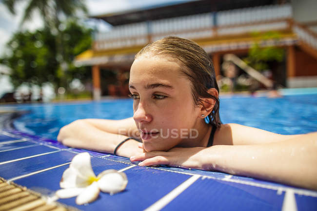 Una chica pensativa se está relajando al lado de una piscina . - foto de stock