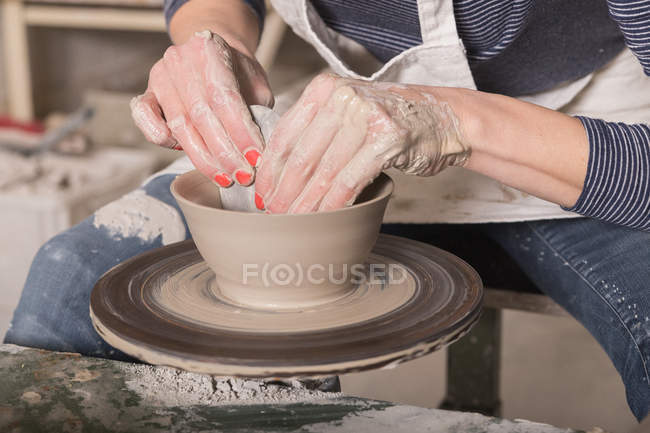 Крупный план женской руки, образующей керамическую глину на гончарном круге в керамической мастерской . — стоковое фото