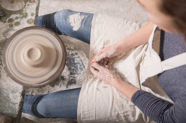 Donna caucasica sta plasmando argilla ceramica su una ruota ceramica in un laboratorio di ceramica . — Foto stock