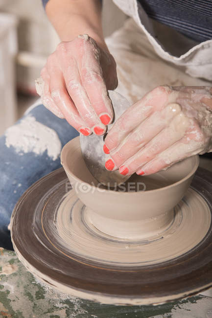 Gros plan de la main d'une femme façonnant de l'argile sur une roue de poterie dans un atelier de céramique . — Photo de stock