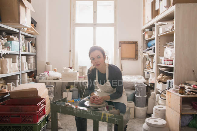 Donna caucasica sta plasmando argilla ceramica su una ruota ceramica in un laboratorio di ceramica . — Foto stock