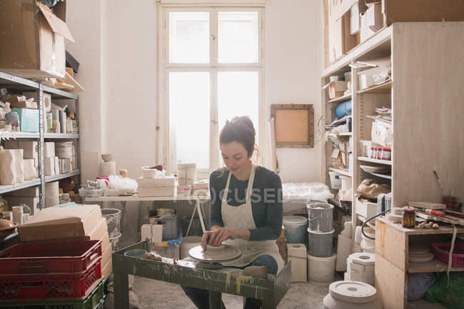 Femme caucasienne façonne l'argile de poterie sur une roue de poterie dans un atelier de céramique . — Photo de stock