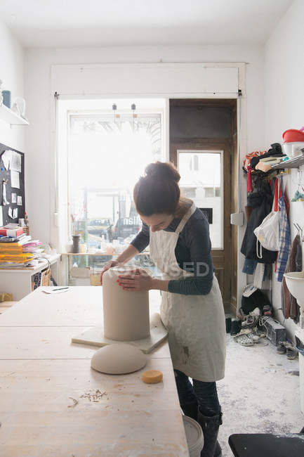 A ceramic artist is putting the finishing touches to a ceramic urn in a ceramic workshop. — Stock Photo