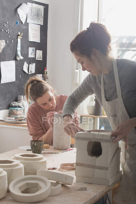 Un artista della ceramica sta mettendo i tocchi finali ad una brocca di ceramica in un laboratorio di ceramica
. — Foto stock
