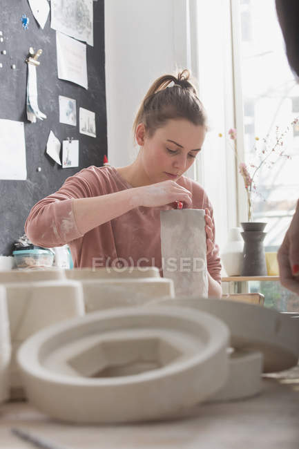 Un artista della ceramica sta mettendo i tocchi finali ad una brocca di ceramica in un laboratorio di ceramica . — Foto stock