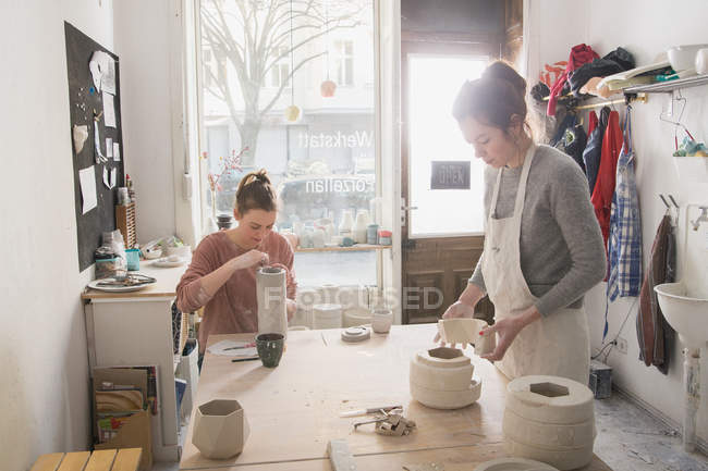 Dos artistas cerámicos están trabajando en su cerámica en un taller de cerámica . - foto de stock