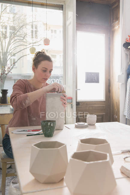 Um artista cerâmico está colocando os toques finais para um jarro de cerâmica em uma oficina de cerâmica . — Fotografia de Stock