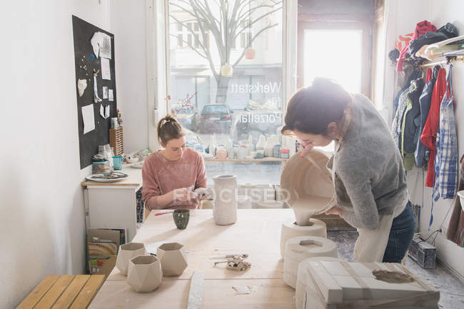 Deux céramistes travaillent sur leurs céramiques dans un atelier de poterie . — Photo de stock
