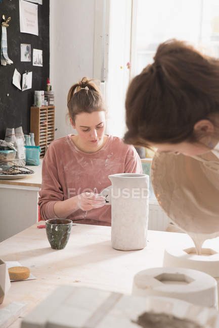 Um artista cerâmico está colocando os toques finais para um jarro de cerâmica em uma oficina de cerâmica
. — Fotografia de Stock