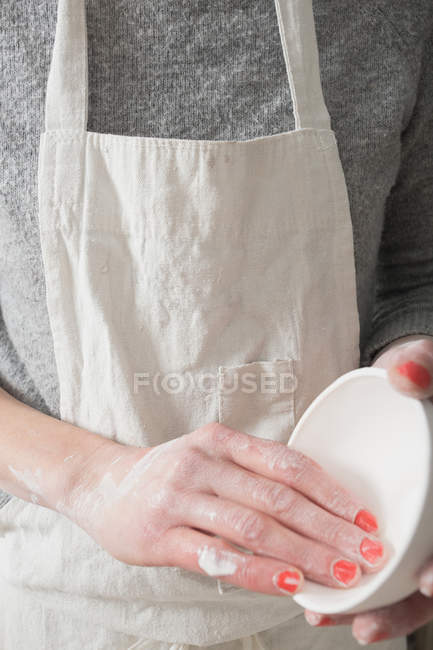 A ceramic artist is holding a bowl in her hands in a pottery workshop. — Stock Photo