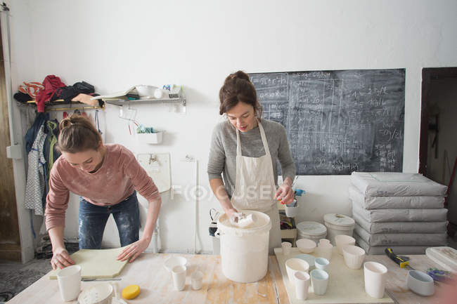 Deux céramistes émaillent des céramiques dans un atelier de poterie . — Photo de stock