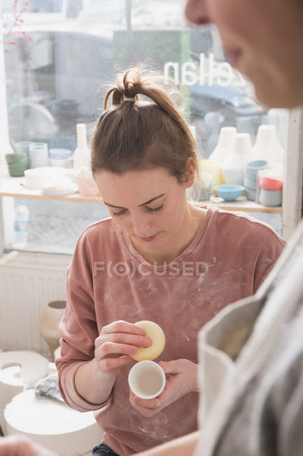 Un artista della ceramica sta mettendo i tocchi finali ad un pezzo di ceramica in un laboratorio di ceramica
. — Foto stock