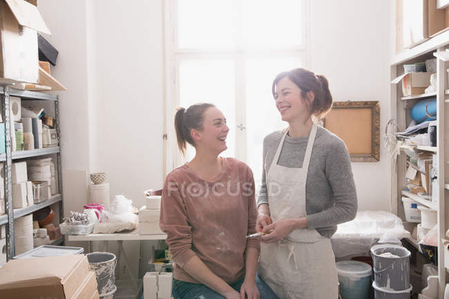 Two smiling ceramic artists portrayed in their pottery workshop. — Stock Photo