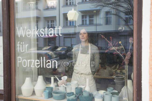 Uma fabricante de cerâmica vista através da janela de sua oficina de cerâmica . — Fotografia de Stock