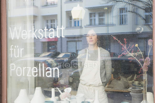 Une céramiste vue à travers la fenêtre de son atelier de poterie . — Photo de stock
