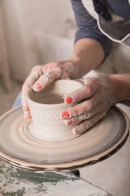 Close up da mão de uma mulher moldando argila de cerâmica em uma roda de cerâmica em uma oficina de cerâmica . — Fotografia de Stock
