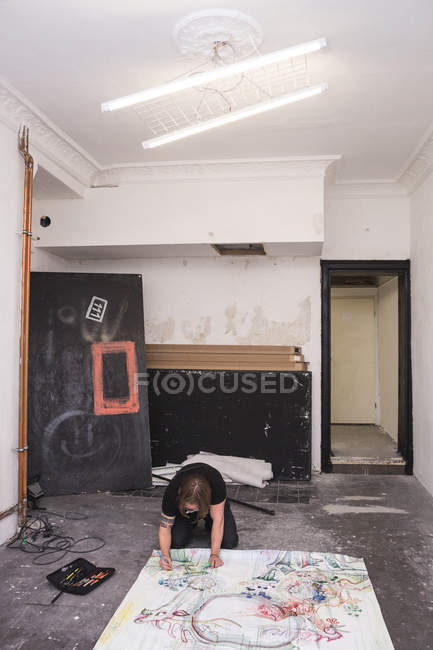 Creative male artist working in his workshop while kneeling over paper — Stock Photo