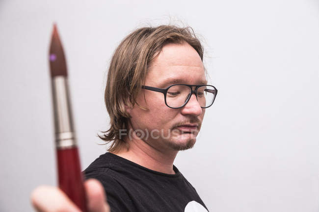 Портрет художника-чоловіка, який працює у своїй майстерні, тримаючи пензлик в руці — стокове фото