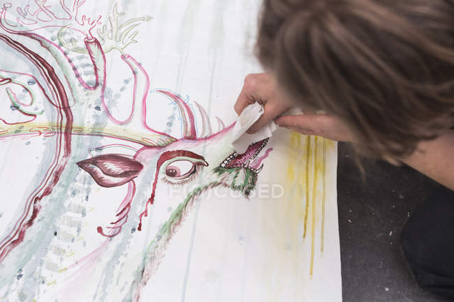 Artista masculino creativo trabajando en su taller mientras pinta sobre papel - foto de stock