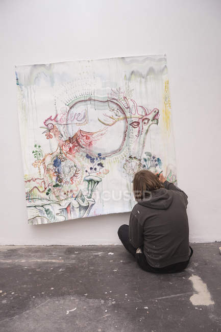 Artiste masculin créatif travaillant dans son atelier et assis sur le sol — Photo de stock