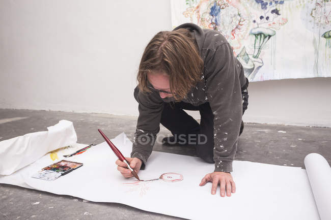 Front view of kneeling Creative male artist working in his workshop. — Stock Photo
