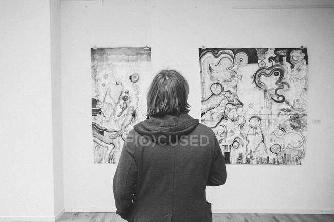Rückansicht eines kreativen männlichen Künstlers, der sein Kunstwerk in einer Kunstgalerie betrachtet. — Stockfoto