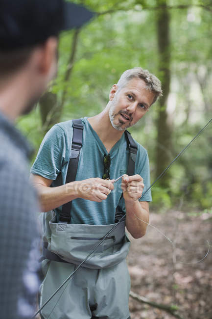 Man in waders is preparing the line for fly fishing. — Stock Photo