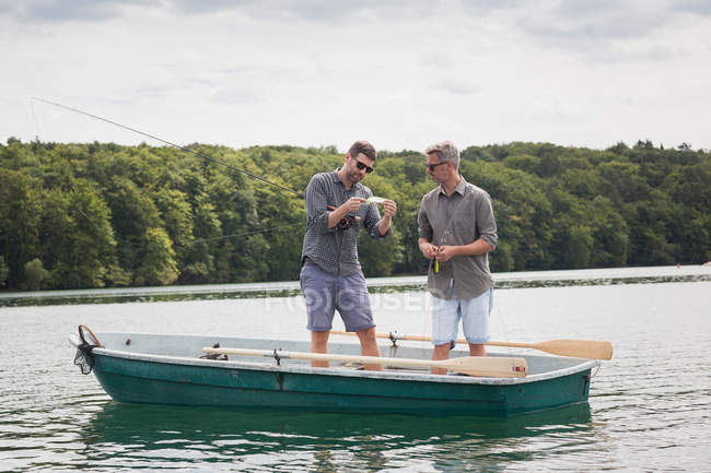 Two caucasian men are preparing their equipment for fly fishing from a boat on lake. — Stock Photo
