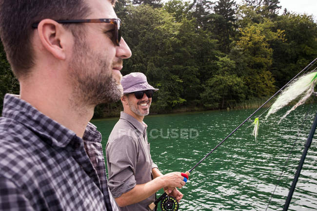 Les hommes caucasiens pêchent à la mouche en bateau sur le lac . — Photo de stock