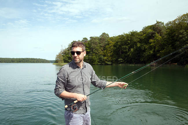 Um homem é pesca com mosca de barco no lago . — Fotografia de Stock