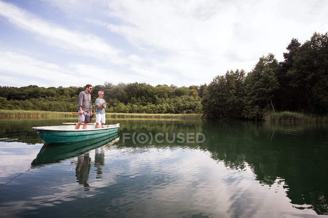 Les hommes caucasiens pêchent à la mouche en bateau sur un lac . — Photo de stock