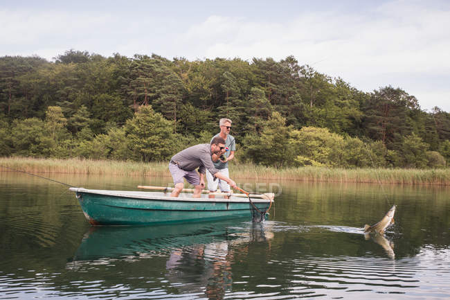 Dos pescadores de moscas han cogido un lucio de un barco en un lago . - foto de stock
