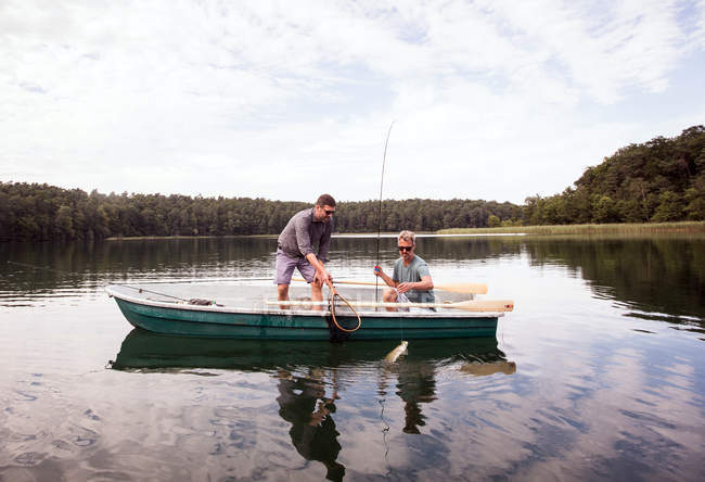 Dos pescadores de moscas han cogido un lucio de un barco en un lago . - foto de stock