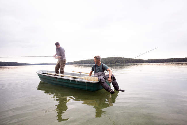 Zwei Männer in Watstiefeln fischen von einem Boot in einem See. — Stockfoto
