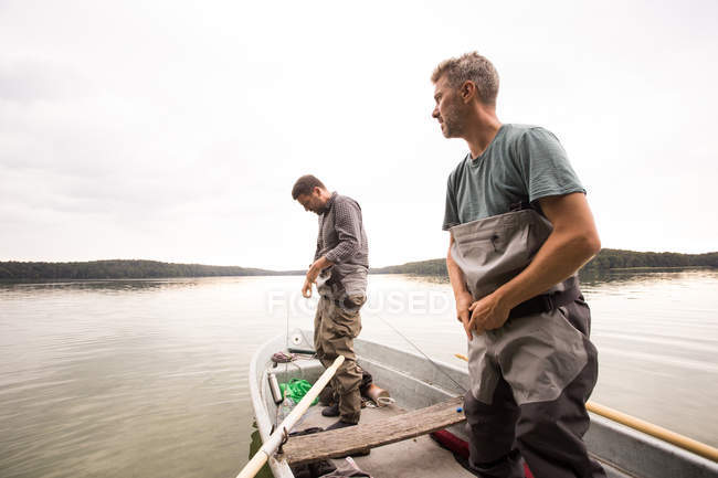 Vor dem Fliegenfischen aus einem See ziehen zwei Männer Watschuhe an. — Stockfoto