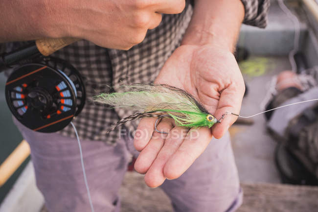 Close up de mosca de pesca em uma mão sobre o barco — Fotografia de Stock