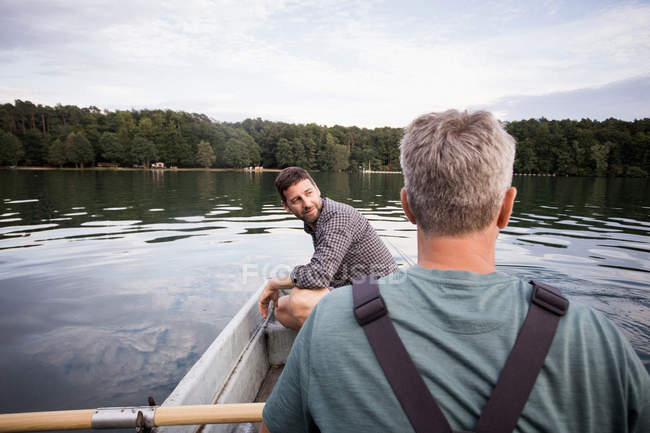 Caucasian men are fly fishing in boat on a river. — Stock Photo