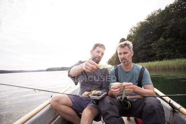 Due uomini stanno raccogliendo una mosca da pesca a mosca affrontare in barca sul fiume . — Foto stock