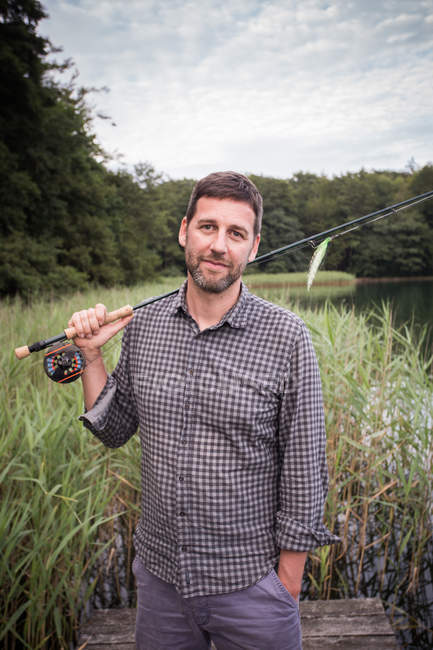 Front view of Caucasian fly fisher with his fishing rod at a lake. — Stock Photo