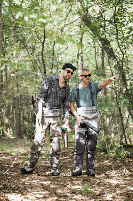 Zwei Männer mit Fliegenfischerausrüstung in Waldgebiet. — Stockfoto