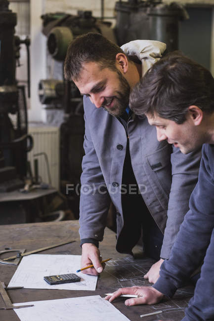 Deux forgerons prennent des mesures, font des calculs et programment une journée de travail dans un atelier de forgeron.
. — Photo de stock