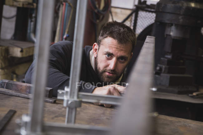 Um ferreiro está tomando medidas em um pedaço de metal em uma oficina . — Fotografia de Stock