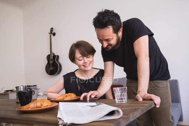 Un jeune couple trompe les médias sociaux sur le téléphone intelligent à la table du petit déjeuner . — Photo de stock