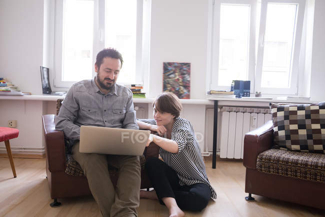 A young couple is browsing the Internet while relaxing in the living room. — Stock Photo