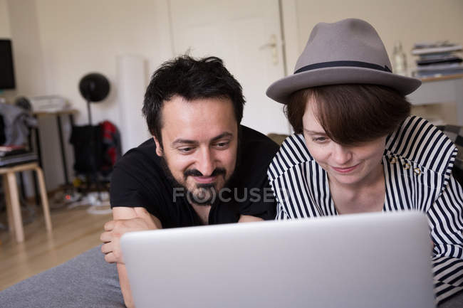 Una joven pareja está navegando por Internet mientras se relaja en el sofá de la sala de estar . - foto de stock