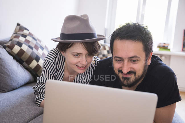 Ein junges Paar surft im Internet, während es sich auf der Couch im Wohnzimmer entspannt. — Stockfoto